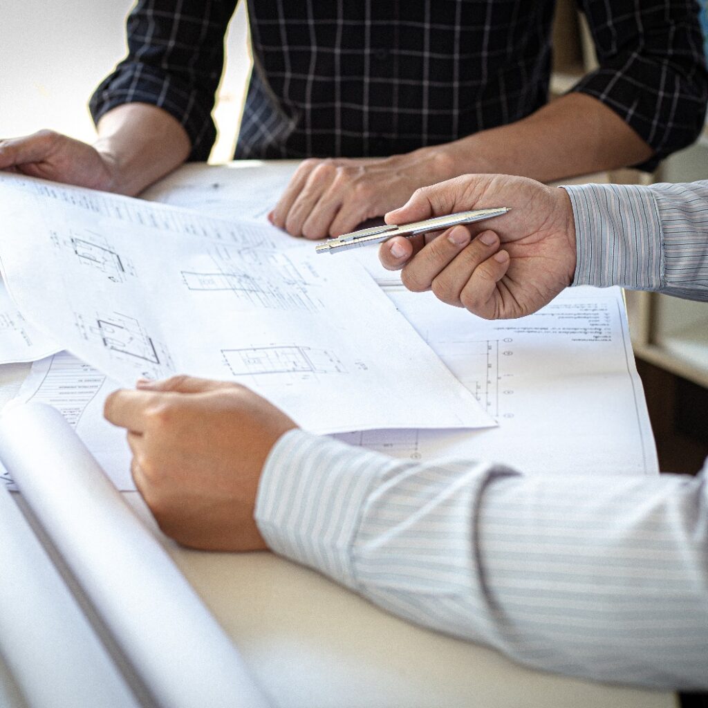Ingenieure oder Architekten treffen sich mit einem Team, um die architektonische Struktur des Entwurfs anhand von Bauplänen und Modellbauten auf der Baustelle sowie die technische Struktur und das Baukonzept zu planen.